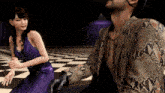 a man in a snakeskin jacket is sitting next to a woman in a purple dress