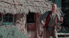 a man is standing in front of a thatched roofed building