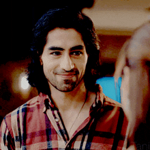 a man in a plaid shirt is smiling and looking at a woman
