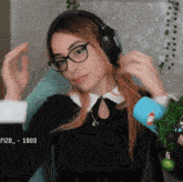 a woman wearing glasses and headphones is sitting in front of a microphone with the number 1000 in the corner