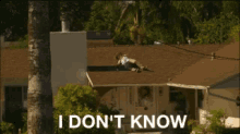 a man is laying on the roof of a house with the words " i don 't know " written below him