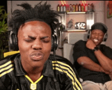 a man wearing headphones is making a funny face while another man laughs