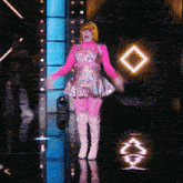 a woman in a pink dress and white boots is standing on a stage