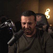 a man covering his face with his hand in front of a microphone that says nike on it