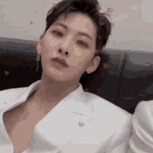 a man in a white jacket is sitting on a couch with hearts on his head .