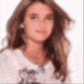 a blurry picture of a woman 's face with long hair and a white shirt .