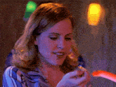 a woman in a blue striped shirt is looking at her phone