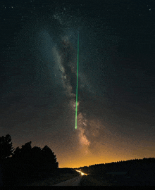 a green light is shining in the night sky