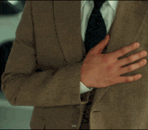 a man in a suit and tie is holding his hand to his chest