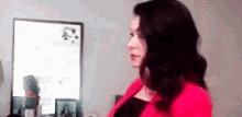 a woman in a red sweater is standing in front of a mirror in a living room .