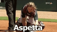 a woman is kneeling down on a baseball field and the word aspetta is on the ground