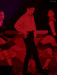 a man in a red shirt is dancing with two women in black dresses in front of a speaker that says hakyunie