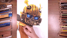 a person is drawing a picture of bumblebee surrounded by various colored pencils