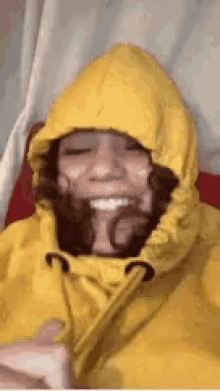 a woman wearing a yellow hooded jacket is smiling