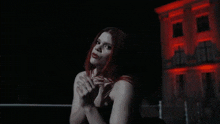 a woman with red hair is standing in front of a building