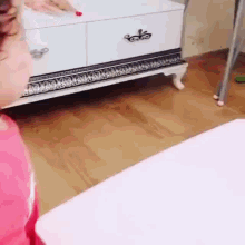 a little girl is sitting at a table in front of a dresser .