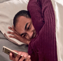 a man wrapped in a blanket is looking at a cellphone