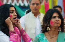 two women are standing next to each other with their faces painted with holi colors