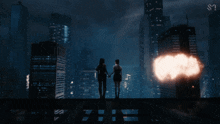 two women standing on top of a building holding hands in front of a city