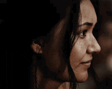 a close up of a woman 's face with a smile on her face in a dark room .