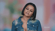 a woman wearing a denim jacket and earrings is making a face .
