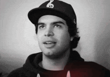 a young man wearing a black hat with a white letter s on it