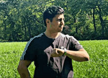 a man wearing a black adidas shirt stands in a field