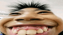 a close up of a person making a funny face with their mouth open and teeth showing .