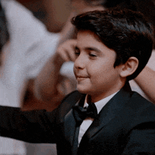 a young boy in a tuxedo and bow tie