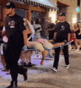 a man wearing a shirt that says emt is carrying another man on a stretcher