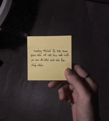 a person is holding a yellow sticky note with a quote on it