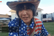 a woman wearing a cowboy hat and an american flag shirt is holding a cell phone