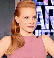 a woman in a pink dress is sitting on a couch with a microphone in her ear .