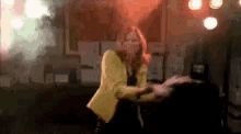 a woman in a yellow jacket is standing next to a man in a room .