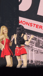 two girls are dancing in front of a monsters sign