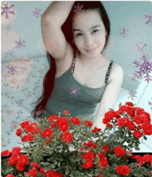 a woman in a tank top stands in front of a bunch of red roses