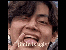 a close up of a person 's face with their tongue out and the words `` jimin is ugly '' written on it .