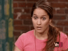 a woman in a pink shirt is making a funny face .