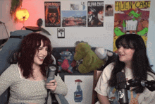 two girls are sitting in front of a wall that has a poster that says alien cake