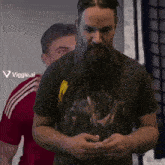 a man with a beard is standing in front of a sign that says ' viggle.ai ' on it