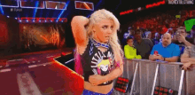 a woman is standing on a stage in front of a crowd while holding her hair .