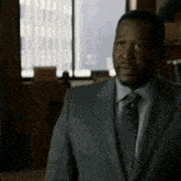 a man in a suit and tie is standing in front of a window