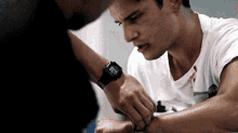 a man with a watch on his wrist looks at another man 's hand