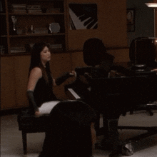 a woman is playing a piano in a room with a poster on the wall that says ' piano '