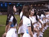 a group of cheerleaders standing on a field with one wearing a shirt that says ' twice ' on the front