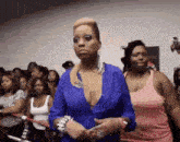 a woman in a blue top is standing in front of a crowd of women .