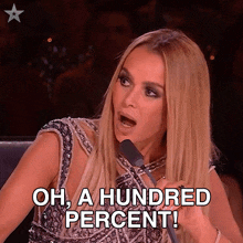 a woman speaking into a microphone with the words oh a hundred percent