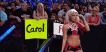 a woman is holding a sign that says carol in front of a crowd .
