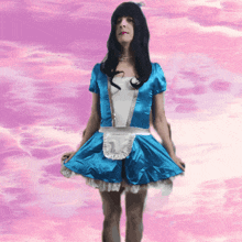 a woman in a blue maid costume stands in front of a pink background