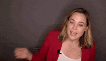 a woman is wearing a red jacket and a white tank top .